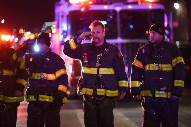 Firefighters salute the ambulance carrying the body of the police officer who was killed in Harlem on January 21, 2022